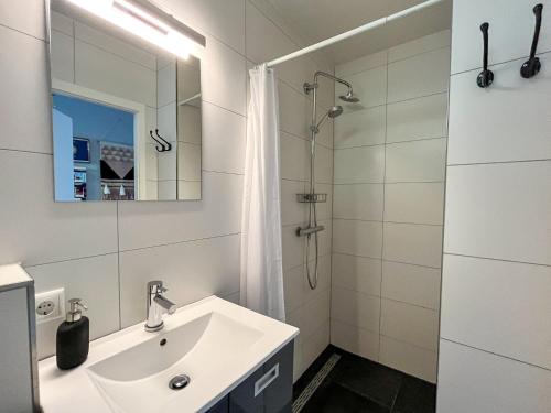 een witte badkamer met een wastafel en een douche bij Modern natuurhuisje midden in het bos op de Veluwe - Beau Home in Otterlo