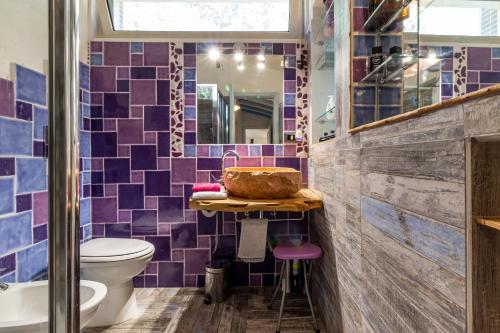uma casa de banho com azulejos roxos, um lavatório e um WC. em Statzu Butzu em Costa Paradiso