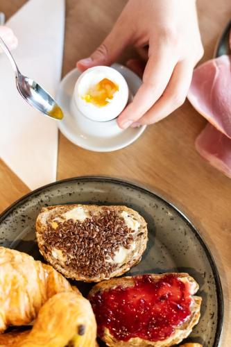 a person holding a plate of food with eggs and toast at B&B HOTEL Geneva Airport in Geneva