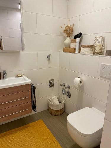 a white bathroom with a toilet and a sink at Bergkristall 304 in Hauzenberg