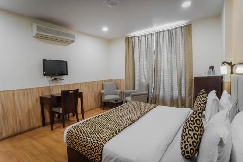 Habitación de hotel con cama, escritorio y TV. en Hotel Royal Palm - A Budget Hotel in Udaipur, en Udaipur