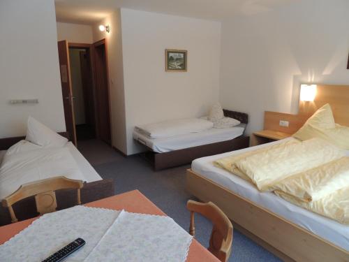 a hotel room with two beds and a table and chairs at Pension Winnebach in Längenfeld