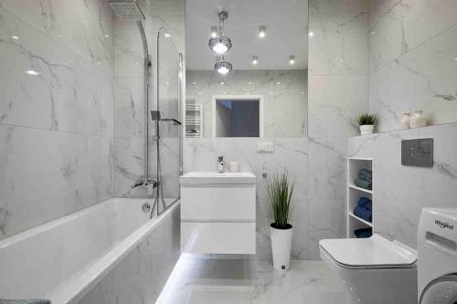 a white bathroom with a tub sink and a toilet at Apartment Olympia in Wrocław