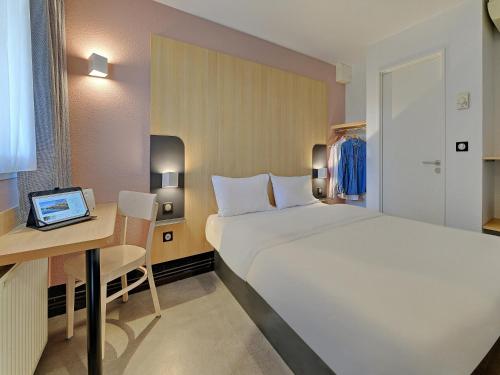 sypialnia z łóżkiem i biurkiem z laptopem w obiekcie B&B HOTEL Le Mans Nord 2 w mieście Saint-Saturnin