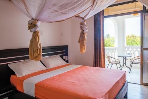 a bedroom with a bed and a balcony with a table at Leomilo Holidays in Diani Beach