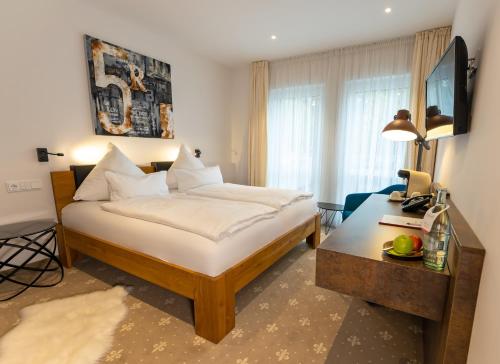 a hotel room with a bed and a desk and window at Landhaus Biewald in Göttingen