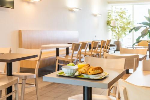 a table with a plate of food on it in a restaurant at B&B HOTEL Lyon Sud États-Unis in Vénissieux