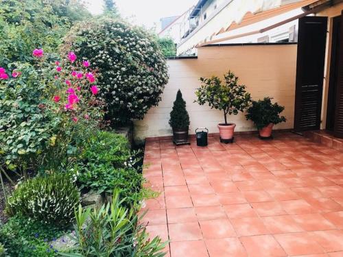 eine Terrasse mit Topfpflanzen und Blumen neben einem Haus in der Unterkunft Ein Zuhause mit schönem Garten in Bonn