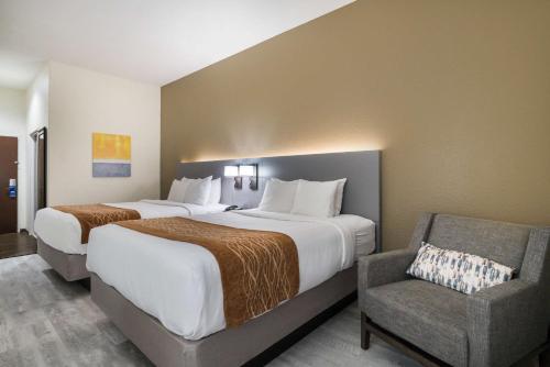 a hotel room with two beds and a chair at Comfort Inn & Suites Victoria North in Victoria