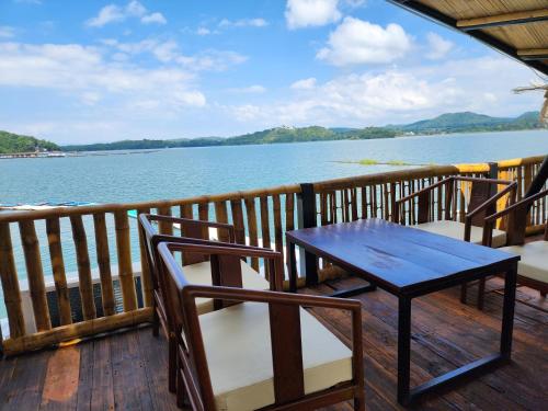 a table and chairs on a deck with a view of the water at บ้านไร่ วรรณ วาลย์ รีสอร์ท in Tha Kradan