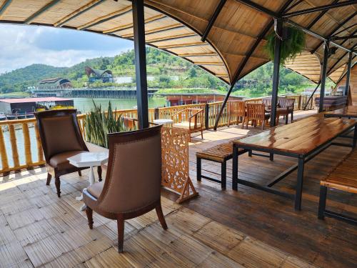 a deck with chairs and a wooden table and benches at บ้านไร่ วรรณ วาลย์ รีสอร์ท in Tha Kradan