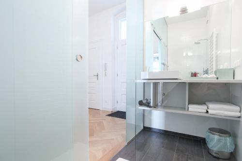 biała łazienka z umywalką i lustrem w obiekcie Pink Grapefruit City Condo w Wiedniu