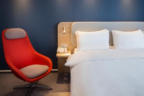 una sedia rossa seduta accanto a un letto in una stanza di Holiday Inn Express Baden-Baden, an IHG Hotel a Baden-Baden