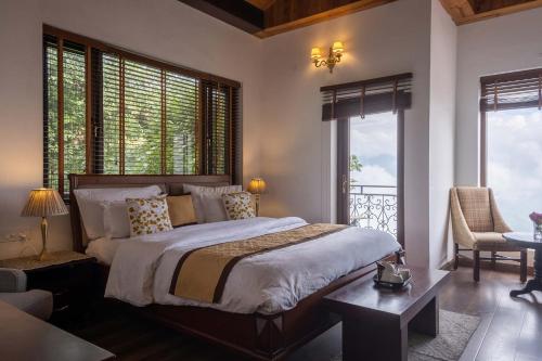 Un dormitorio con una cama y una mesa y ventanas. en StayVista at Slice of Heaven, en Mussoorie