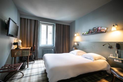 a hotel room with a large bed and a television at Hotel Beaulieu Lyon Charbonnières in Charbonnières-les-Bains