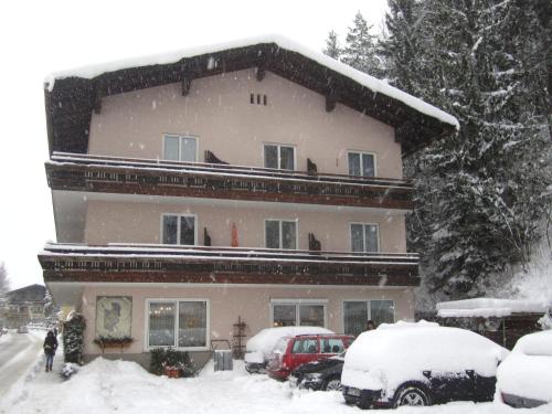 a snow covered house with cars parked in front of it at Pension Vocario in Pfarrwerfen