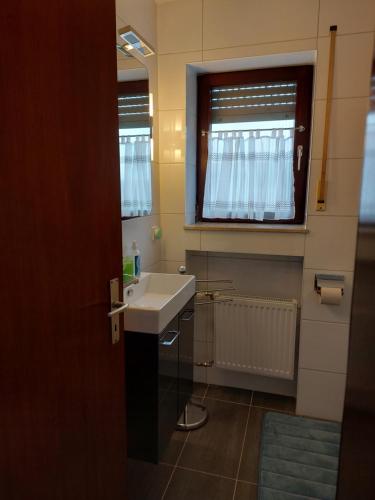 ein Bad mit einem weißen Waschbecken und einem Fenster in der Unterkunft FeWo1&Dreibettzimmer in Bad Wurzach