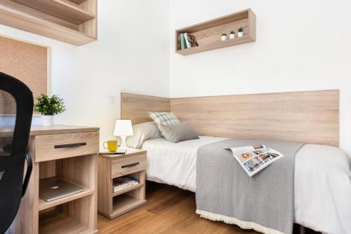 - une chambre avec un lit et une tête de lit en bois dans l'établissement Micampus Armendariz Student Residence, à Séville