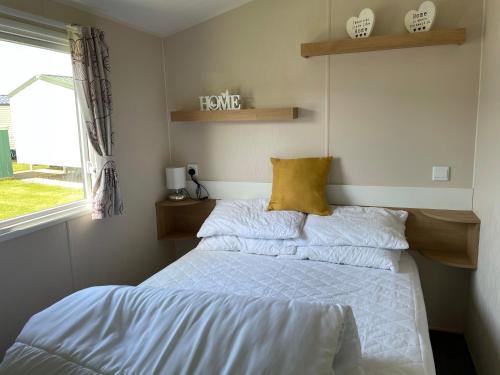 1 dormitorio con 2 camas con sábanas blancas y ventana en Beautiful Butlins van, en Lincolnshire