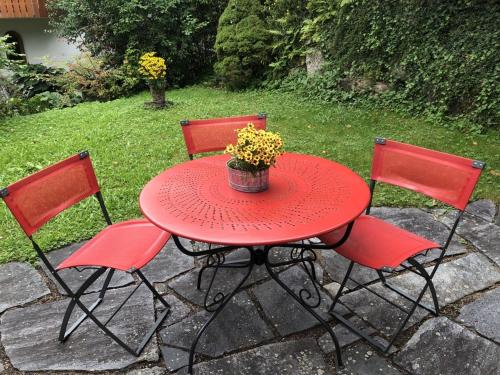 una mesa roja con tres sillas y una maceta en ella en Dreiländereck, schöne Ferienwohnung mit großem Freisitz, en Rheinfelden