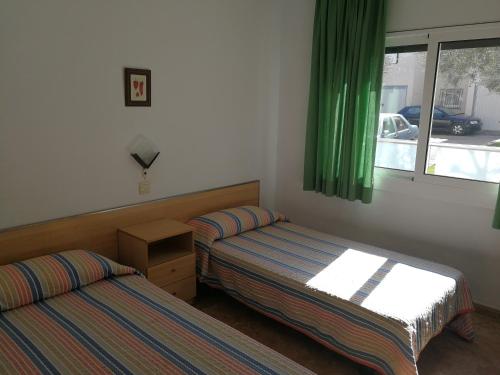 2 łóżka w pokoju z zielonymi zasłonami i oknem w obiekcie Apartment with community pool for 4 people - Riells area w mieście L'Escala