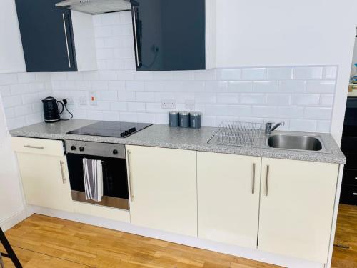 una cocina con armarios blancos y fregadero en Midland Apartment- Studio en Leicester