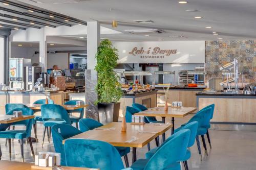 a restaurant with wooden tables and blue chairs at SIGNATURE BLUE RESORT in Kusadası