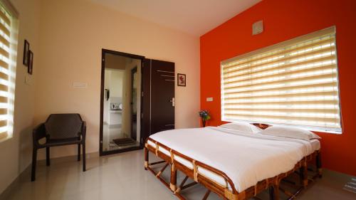 a bedroom with a bed and a window and a chair at Vrindhavan Mist City Resorts in Kanthalloor