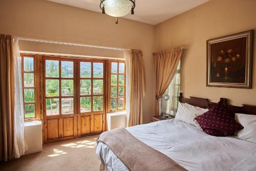 a bedroom with a bed and a large window at Lake Clarens Guest House in Clarens