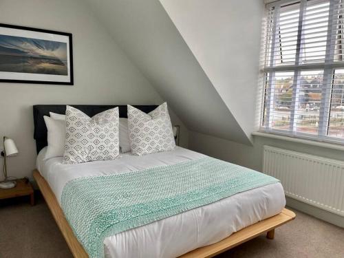 a white bedroom with a bed with pillows and a window at Neap Tide in Rye