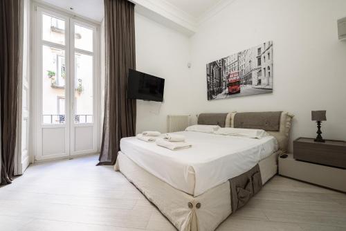 a white bedroom with a large bed and a window at Palazzo dello Spagnolo Suite in Naples