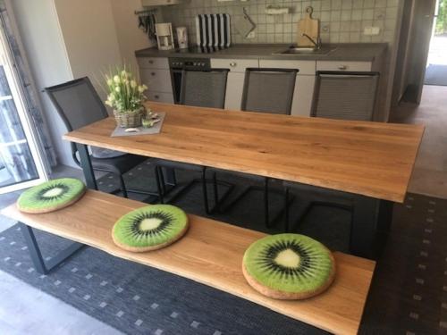 three kiwis sitting on a wooden table in a kitchen at Bungalow 6091 in Tossens in Butjadingen OT Tossens