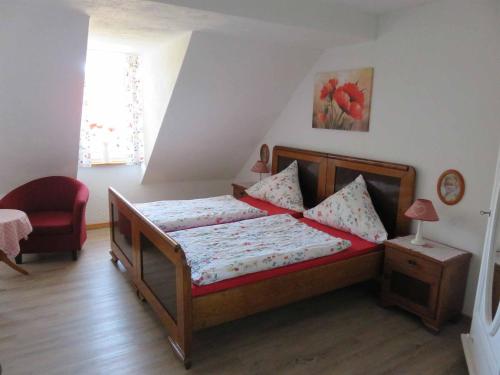 a small bedroom with a bed and a red chair at Pension Gestüt Morgenstern in Hameln
