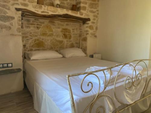 a bed in a bedroom with a stone wall at Little cellar in Chora Folegandros