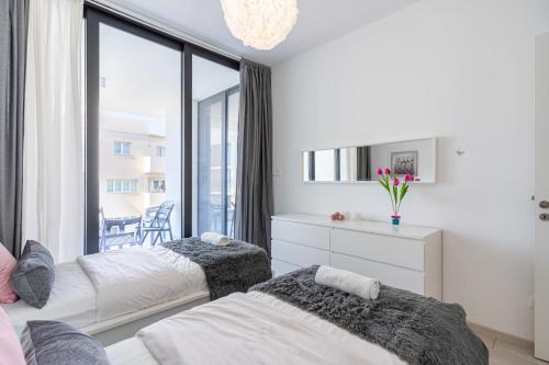 a bedroom with two beds and a large window at Aziza 1- Bedroom Apartment in Larnaca in Larnaka