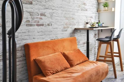 - un canapé orange dans une chambre avec un mur en briques dans l'établissement Le Sunny Duplex hypercentre la plage à 2 pas !, à Les Sables-dʼOlonne