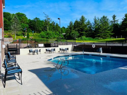 una piscina con sillas, una mesa y una valla en Holiday Inn Express Blowing Rock South, an IHG Hotel, en Blowing Rock