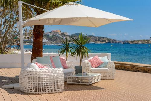 twee stoelen en een paraplu op een terras naast het water bij Hotel Vibra Algarb in Playa d'en Bossa