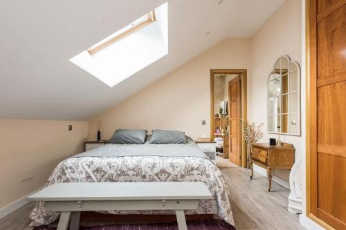 a white bedroom with a bed and a skylight at Ático con terraza y chimenea junto a Universidad in Alcalá de Henares