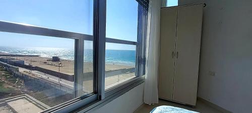 a room with a window with a view of the ocean at Hotel Apartment Short Term Tel Aviv Bat Yam 5 in Bat Yam
