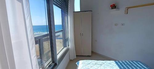 a bedroom with a view of the ocean from a window at Hotel Apartment Short Term Tel Aviv Bat Yam 5 in Bat Yam