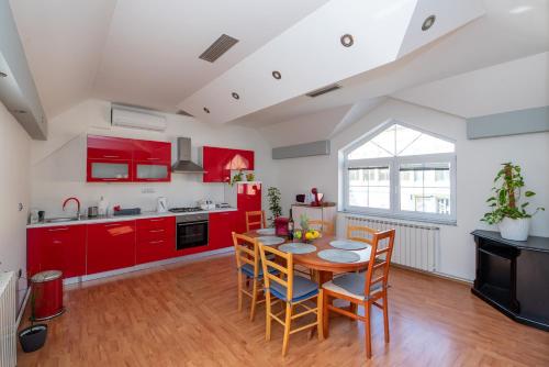 uma cozinha com armários vermelhos e uma mesa com cadeiras em Apartman Lega - Daruvar em Daruvar