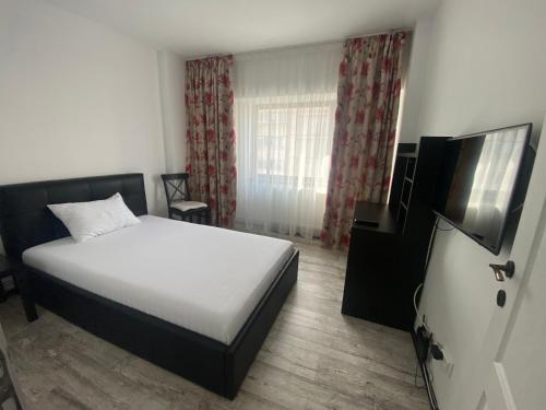 a bedroom with a bed and a flat screen tv at Violetta Apartament in Buzău