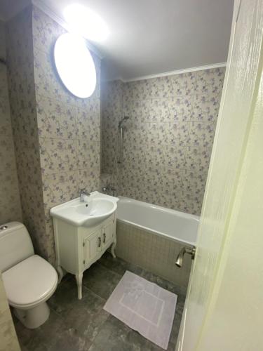 a bathroom with a toilet and a sink and a tub at Violetta Apartament in Buzău