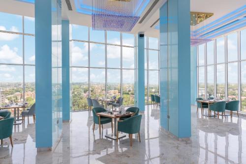 un restaurante con mesas, sillas y ventanas grandes en Pyramid Continental Hotel en Yuba