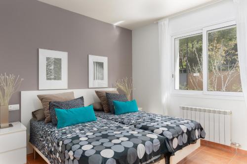 een slaapkamer met een bed met blauwe kussens en een raam bij MAR DE PINS in Tamariu