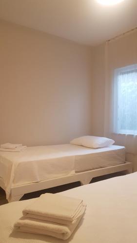 a white bedroom with two beds and a window at Hotel Villa Monte in Cıralı