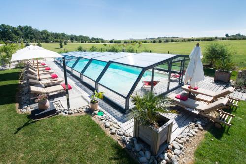 - une vue sur la piscine avec des chaises et un parasol dans l'établissement Gîte Domaine de Nazère, à Avezan