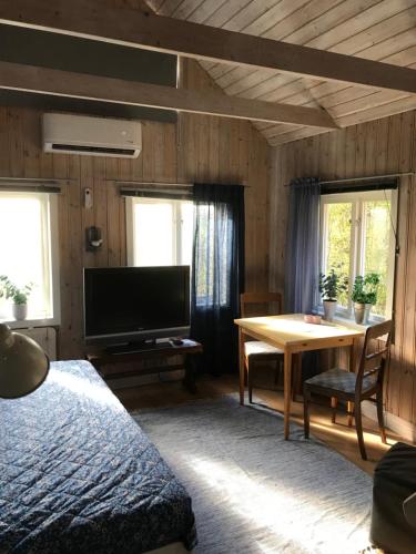 a bedroom with a bed and a table and a television at Trevlig stuga på landet, centralt 8km från Centrum in Eskilstuna