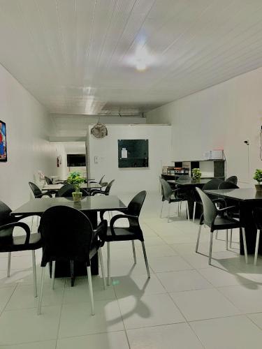 a dining room with tables and black chairs at Pousada Marahub in Maragogi